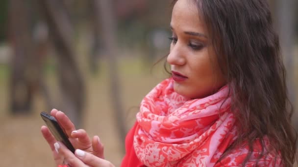 Młoda kobieta, przeglądanie Internetu w telefonie, wiadomości tekstowe i rozmawiać na zewnątrz. — Wideo stockowe