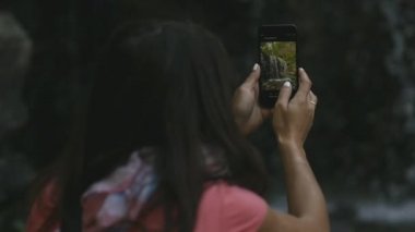 genç kadın bir şelale bir smartphone cep telefonu ile seyahat ederken alır