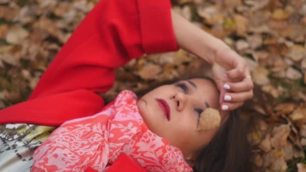 Portrait de fille, qui se trouve sur le feuillage d'automne dans le parc — Video