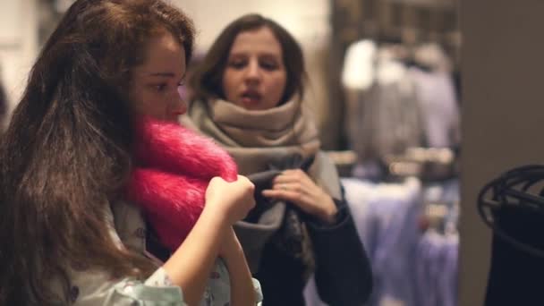 Twee jonge vrouwen shoppen bij het kiezen van de warme winter kleding winkel — Stockvideo