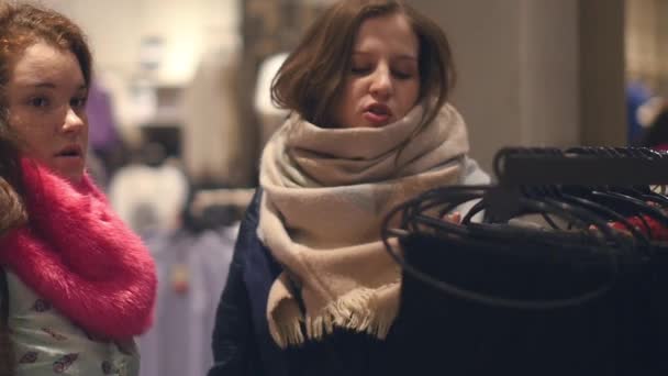 Twee jonge vrouwen shoppen bij het kiezen van de warme winter kleding winkel — Stockvideo