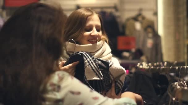 Dos mujeres jóvenes compran en la tienda eligiendo ropa de invierno caliente — Vídeos de Stock