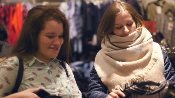 Twee jonge vrouwen shoppen bij het kiezen van de warme winter kleding winkel — Stockvideo