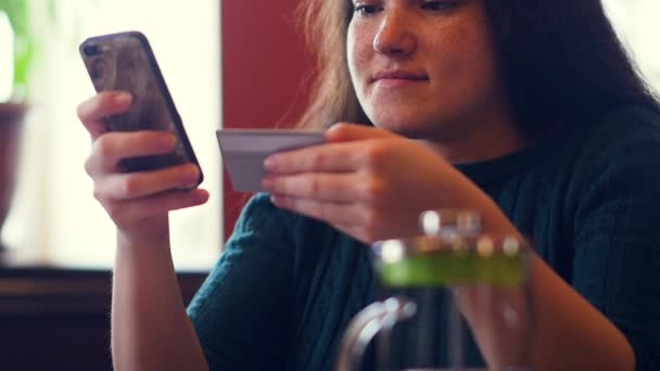 Mujer joven de compras en línea usando una tarjeta de crédito usando un teléfono inteligente . — Vídeos de Stock