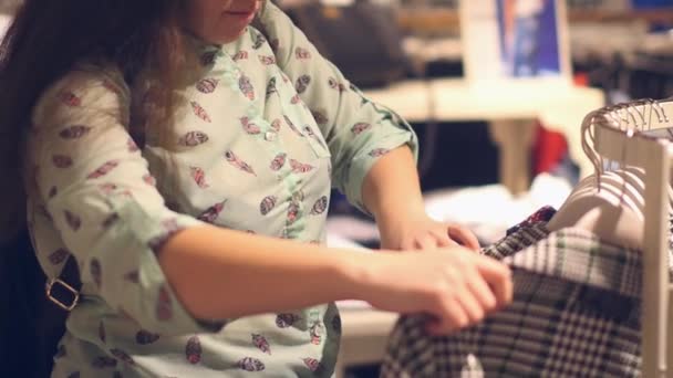 Een jonge vrouw in de winkel Kies warme winterkleren — Stockvideo