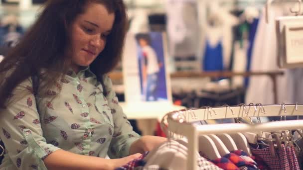 Una mujer joven en la tienda elegir ropa de invierno caliente — Vídeo de stock