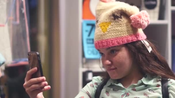 Μια νεαρή γυναίκα στο κατάστημα επιλέξτε ζεστά χειμωνιάτικα ρούχα — Αρχείο Βίντεο