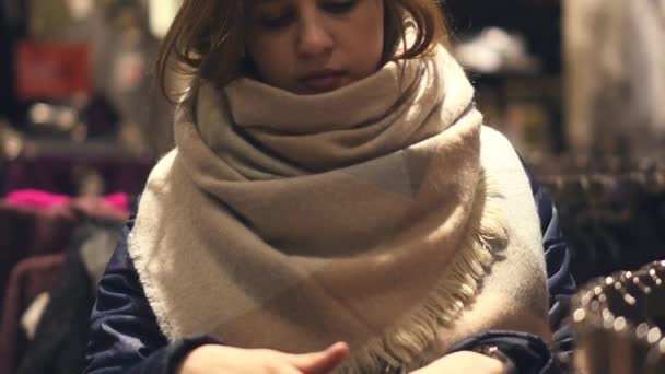 Eine junge Frau im Laden wählt warme Winterkleidung — Stockvideo