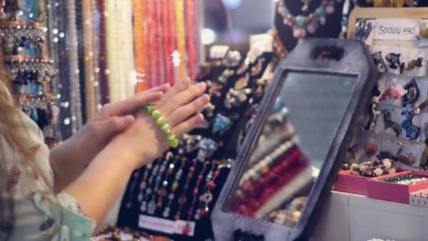 Een jonge vrouw probeert op armbanden op de markt — Stockvideo