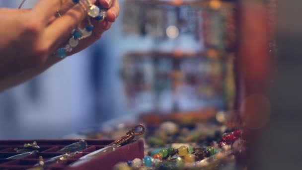 Een jonge vrouw probeert op armbanden op de markt — Stockvideo