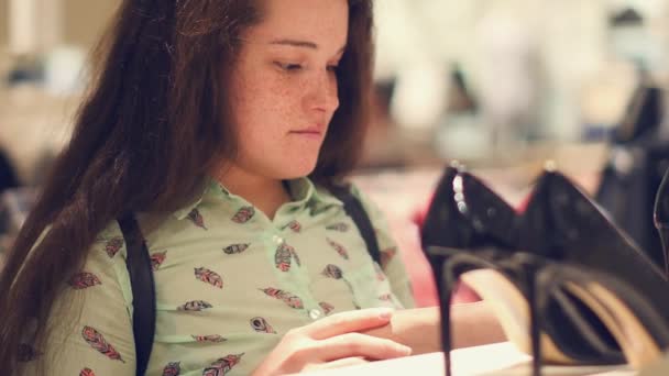 Una mujer joven en la tienda elegir los zapatos de la semi-temporada — Vídeos de Stock