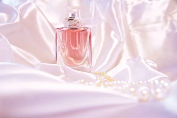 A beautiful bottle of perfume on the background of silk. Fashion & Style. — Stock Photo, Image