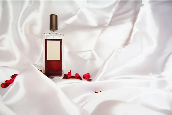 Butelkę perfum na tle jedwabiu. Moda styl idealna. Płatki róż. — Zdjęcie stockowe