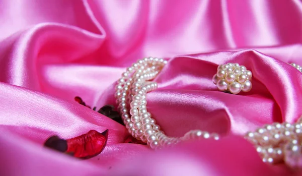 Beautiful pearls on a background of pink silk. Fashion & Style. Necklace and earrings. — Stock Photo, Image