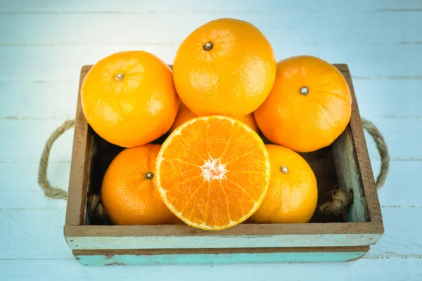 Frutas frescas de naranja entera y naranja en rodajas sobre fondo de madera —  Fotos de Stock