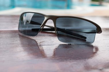 Yüzme Havuzu yanında kahverengi ahşap masa üzerinde güneş gözlüğü