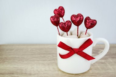 Parlak kırmızı kalp ve kurdele ile süslenmiş beyaz kahve fincanı