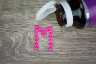 Pembe ahşap arka plan M alfabesine şekillendirme şekle hap