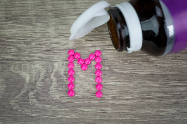 Pembe ahşap arka plan M alfabesine şekillendirme şekle hap