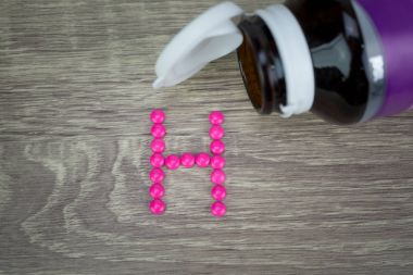 Pembe ahşap arka plan H alfabesine şekillendirme şekle hap