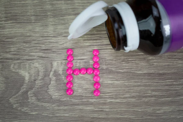 Pembe ahşap arka plan H alfabesine şekillendirme şekle hap