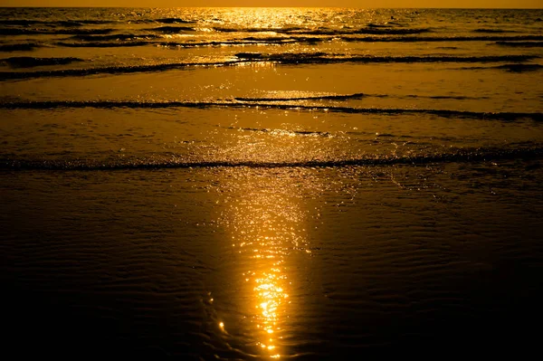 Luz do pôr do sol superfície de água cintilante na praia tropical — Fotografia de Stock