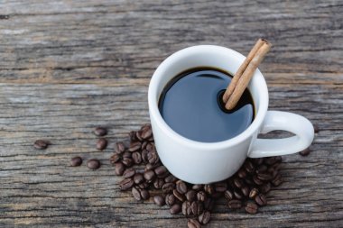 Sıcak kahve ile kahve çekirdekleri ahşap arka plan üzerinde beyaz kupa