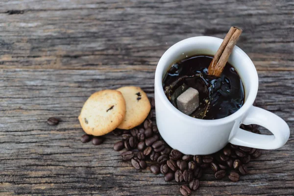 Cubo de azúcar moreno cayendo en taza de café caliente con granos de café — Foto de Stock