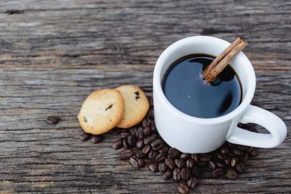 Café caliente en taza blanca con granos de café y galletas en madera ba — Foto de Stock