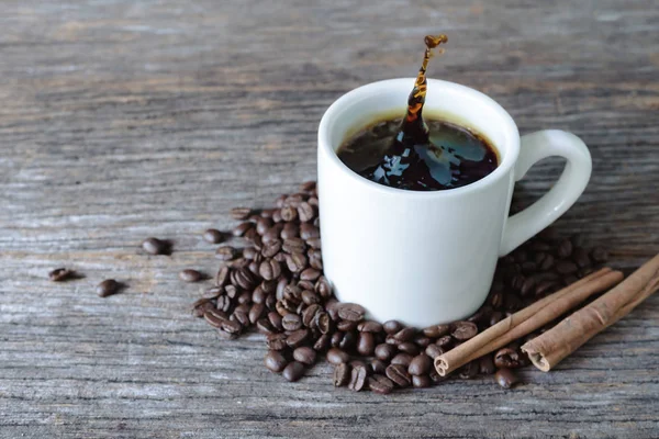 Café caliente en taza blanca con granos de café sobre fondo de madera — Foto de Stock