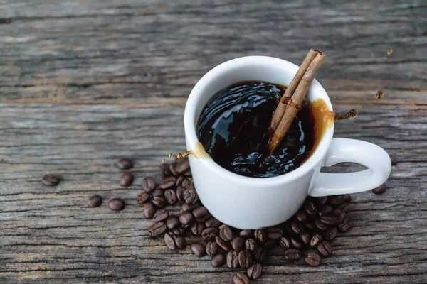 Café caliente en taza blanca con salpicaduras y granos de café en bac de madera — Foto de Stock