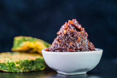 Baharatlı biber ezmesi ve koyu arkaplanda gıdaklayan kızarmış yumurta.