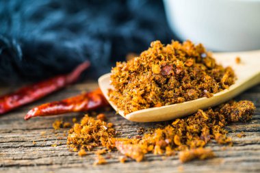 Baharatlı kurutulmuş balık, ahşap kaşık ve arka planda acı biber ezmesi.