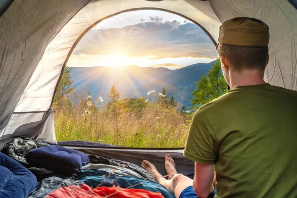 Turista se probudil časně ráno a díval se ze stanu na hory. Turistický stan, pozadí — Stock fotografie