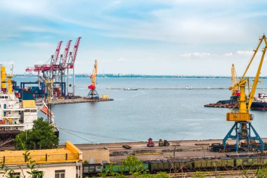 Gemi ve vinçler bir yaz günü deniz limanında yük yükler ve boşaltırlar.