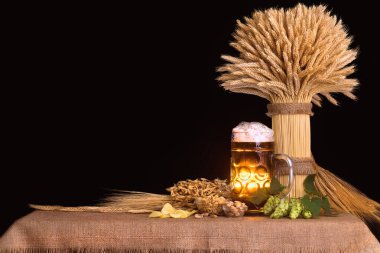 beer, hops, snacks, ingredients for making beer and sheaf of wheat on the table, dark background clipart