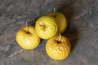 Wrinkled yellow old apples lies on the table top, closeup on neutral background. clipart