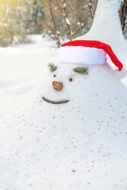 Neşeli kar yığını, kardan adam, Noel şapkasıyla, karlı bir kış ormanında Noel tatili bekleyerek.