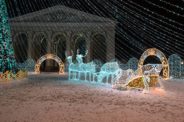 Noel geyiği. Dışarıdaki çelenkler sokağı süslüyor. Noel arifesinde sokakta bir geyik şeklinde tatil ışıkları. Sokakta oyuncaklarla Noel ağacı.