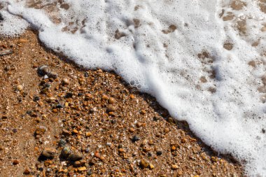 Dalgalar Brighton sahilinde çakıl taşlarını yuvarlıyor.