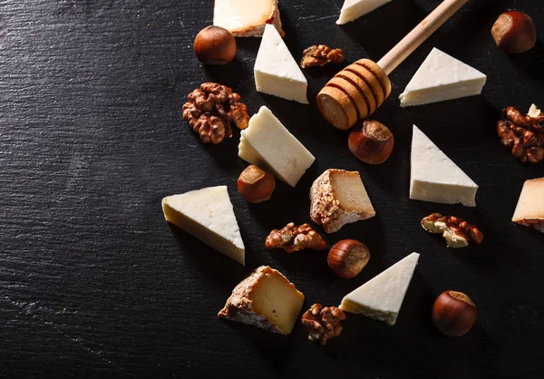 Käse mit Nüssen auf einem dunklen Steinteller. — Stockfoto