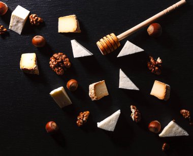 karanlık bir taş plaka üzerinde fındık ile peynir.