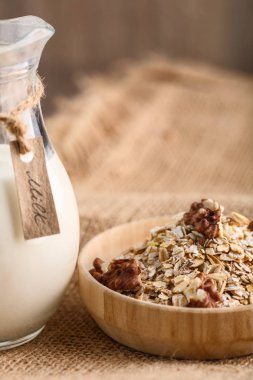 Kuru haddelenmiş yulaf ezmesi Tekstil zemin üzerine ahşap kase.