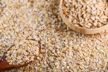 Ahşap kase ve tahta kaşık yulaf ezmesi arka plan üzerinde rulo yulaf ezmesi kuru. Üstten Görünüm.