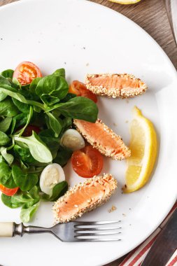 Susam, kiraz domates ve ahşap masa üstünde Bıldırcın yumurta salatası Somon ızgara