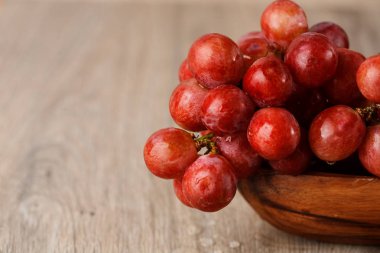 ahşap bir fincan kırmızı üzüm demet