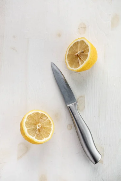 one lemon cut in half with metal knife