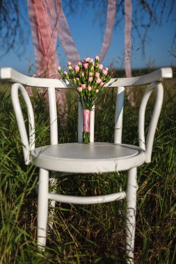 çim sahada arasında beyaz bir sandalyeye pembe karanfil buketi