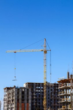 Mavi gökyüzü arka planında çok katlı bir bina inşa ediliyor.