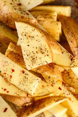 Çiğ patates dilimleri bir pişirme çanağı içinde baharatlar ile